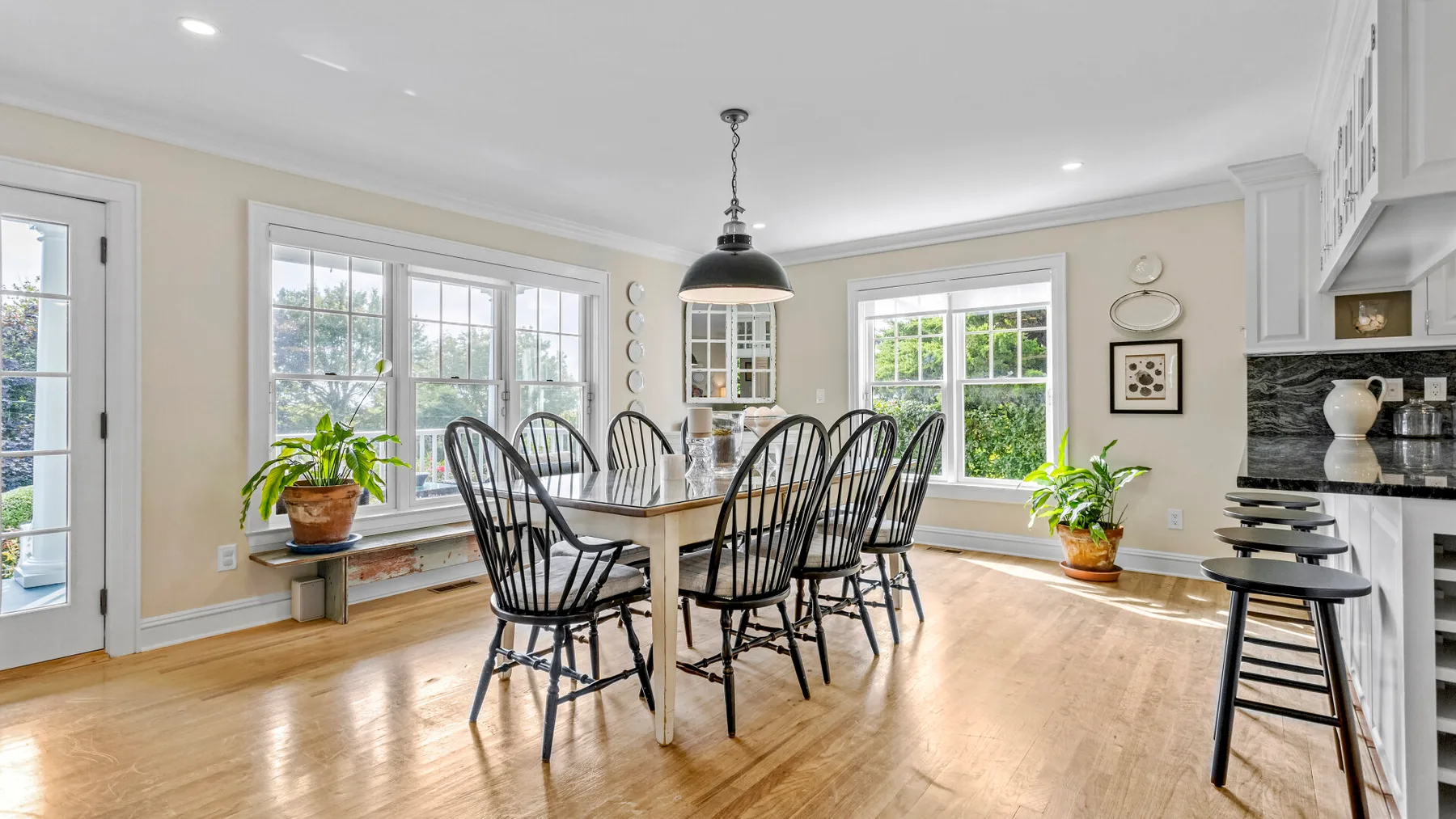 Un comedor luminoso con una mesa y sillas junto a grandes ventanas.