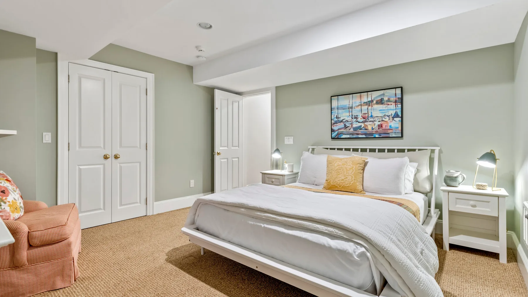 Un dormitorio con una cama, mesitas blancas y una obra enmarcada.