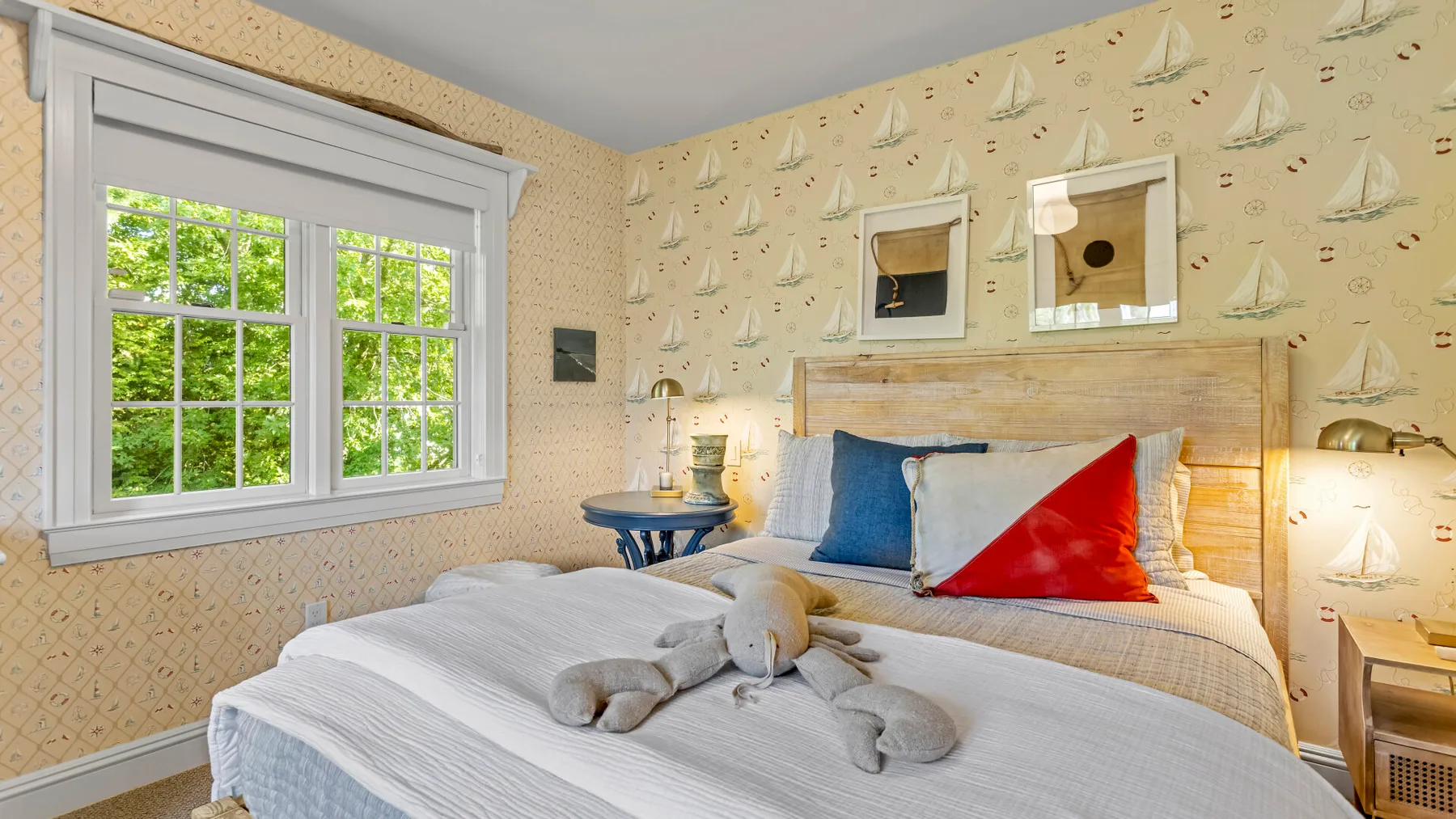 Un dormitorio con una cama bien hecha y papel tapiz con motivos de veleros.