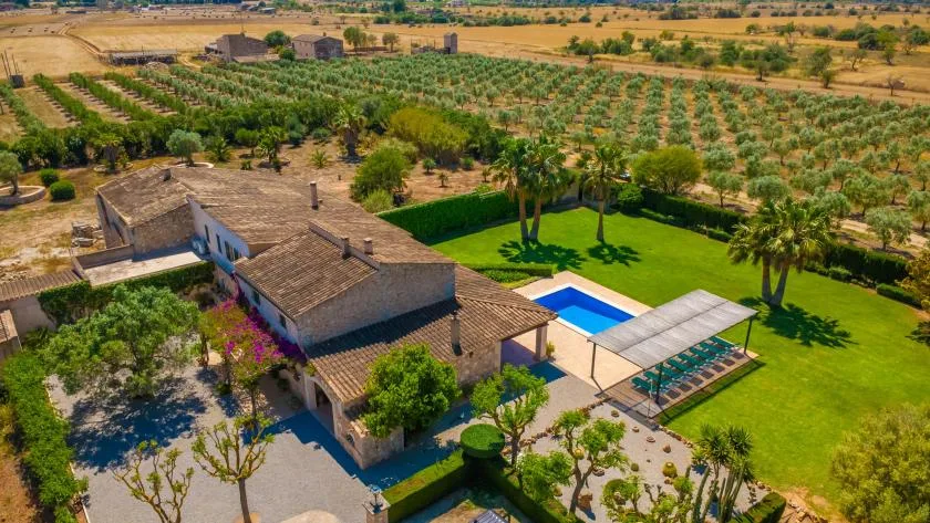 Vista aérea de una propiedad rural con piscina y huertos alrededor.