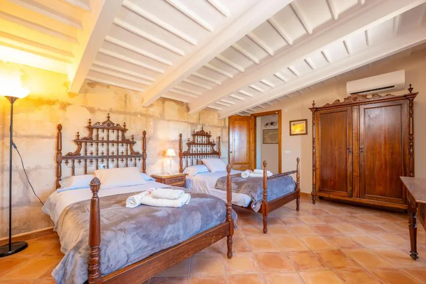 Un dormitorio con dos camas, muebles de madera y un techo blanco con vigas.