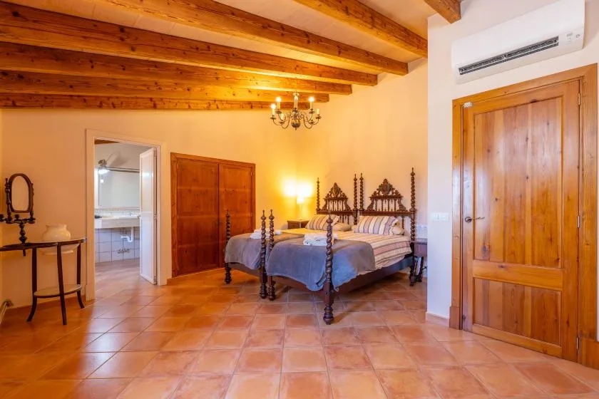 Un dormitorio con una cama grande de madera, suelo de baldosas y vigas a la vista.