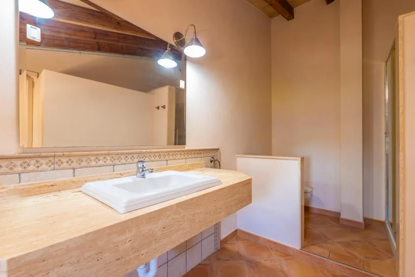 Un lavabo de baño con un espejo amplio y suelo de baldosas.