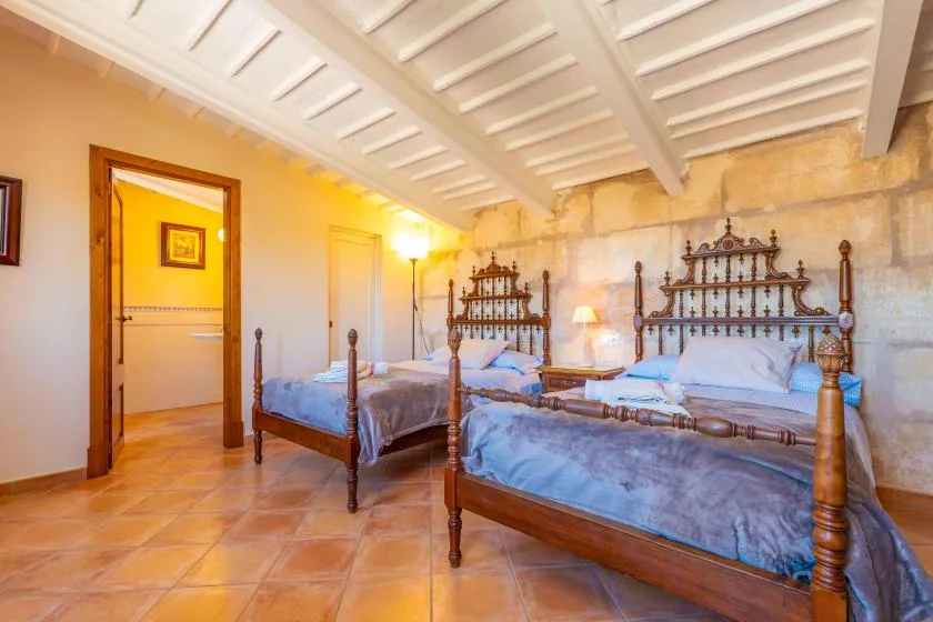 Un dormitorio con dos camas de madera bajo un techo blanco con vigas.