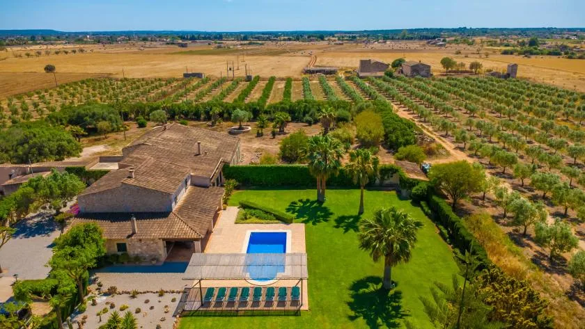 Vista aérea de una casa rural con jardín, piscina y campos alrededor.