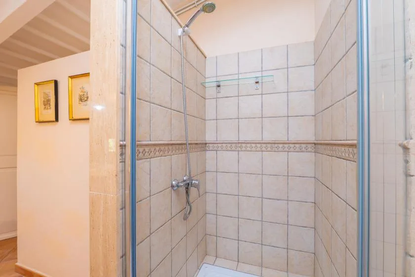 Una ducha revestida de azulejos con cerramiento de vidrio y rociador mural.
