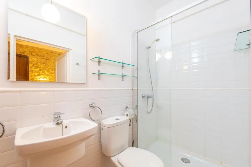 Un baño luminoso con lavabo, inodoro y ducha con mampara de vidrio.
