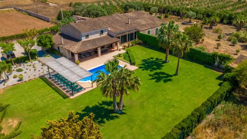Vista aérea de una casa con piscina y un amplio césped verde.