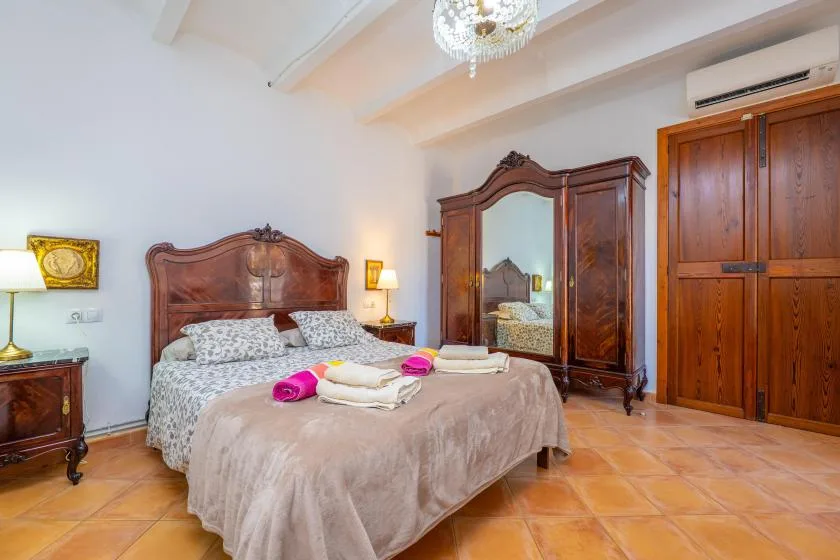 Un dormitorio con una cama doble, muebles de madera y suelo de baldosas color terracota.