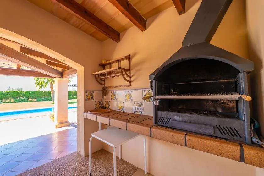 Una cocina exterior con una parrilla grande junto a un patio abierto.