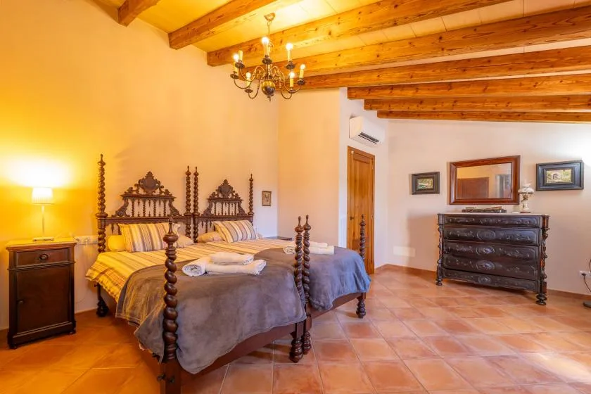 Un dormitorio con dos camas, vigas de madera en el techo y una cómoda oscura.