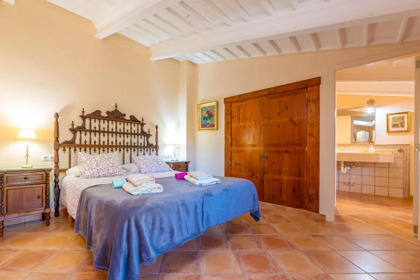Un dormitorio con una cama, una puerta de madera y un acceso abierto a un baño con azulejos.