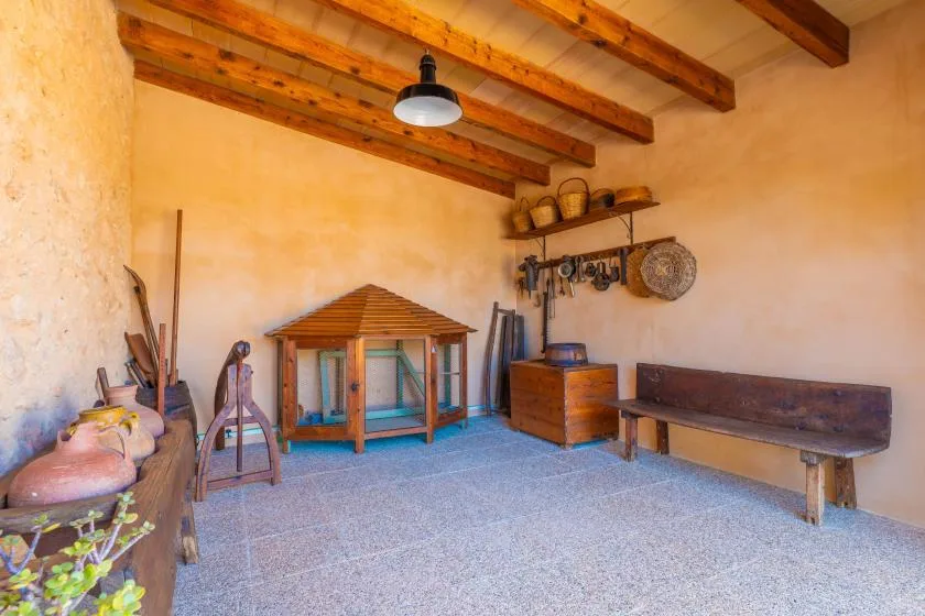Una sala rústica muestra muebles de madera y cerámica bajo vigas de techo expuestas.