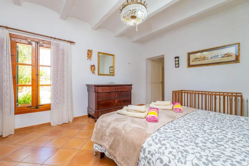 Un dormitorio con una cama de madera, ropa de cama estampada y una cómoda.
