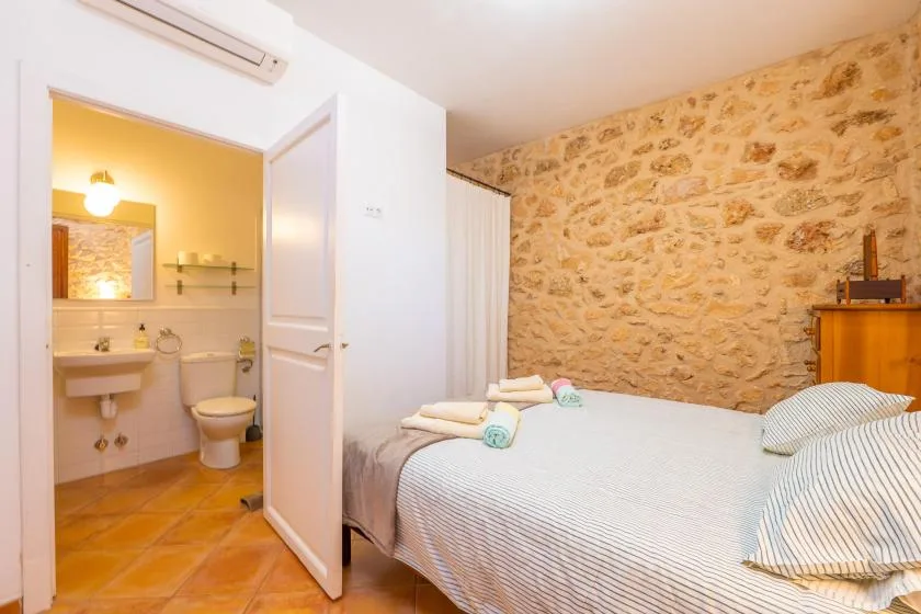 Un dormitorio con una cama junto a una puerta abierta que da a un baño.