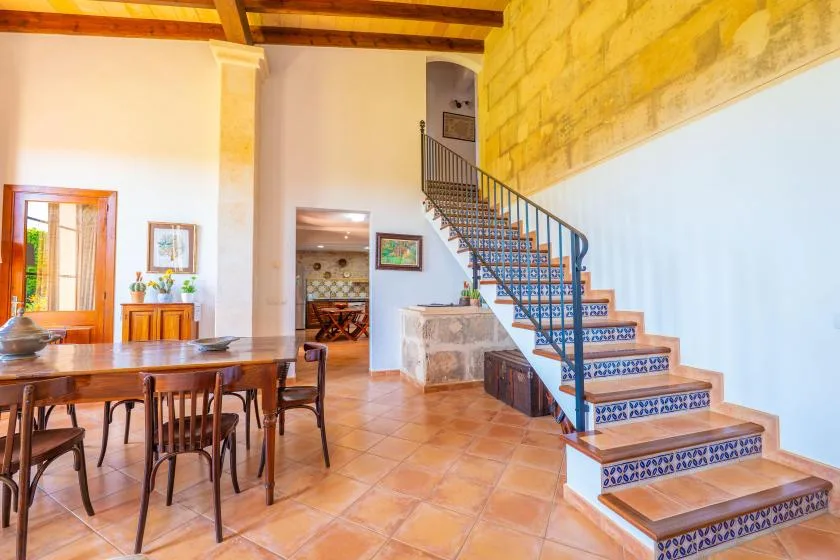 Un comedor se abre a una escalera con contrahuellas de azulejos estampados.