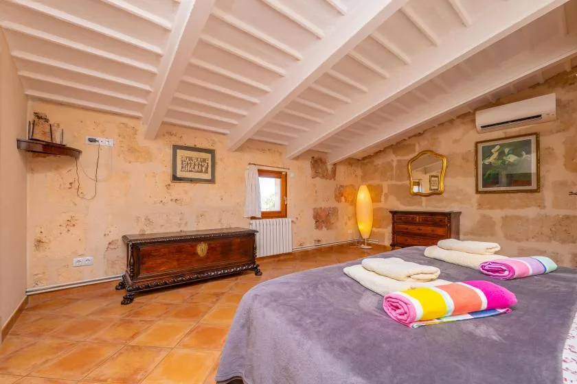 Un dormitorio con una cama, toallas dobladas y vigas expuestas en el techo.