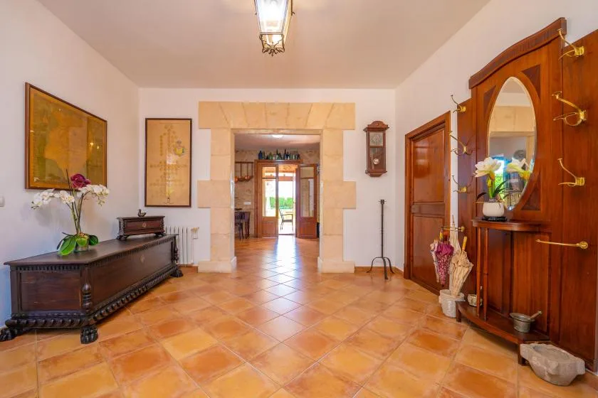 Un recibidor con suelo de baldosas, muebles de madera y una amplia abertura a otra habitación.