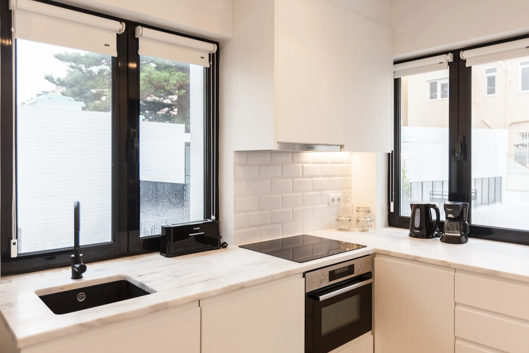 A bright kitchen with a sink, cooktop, and large windows.
