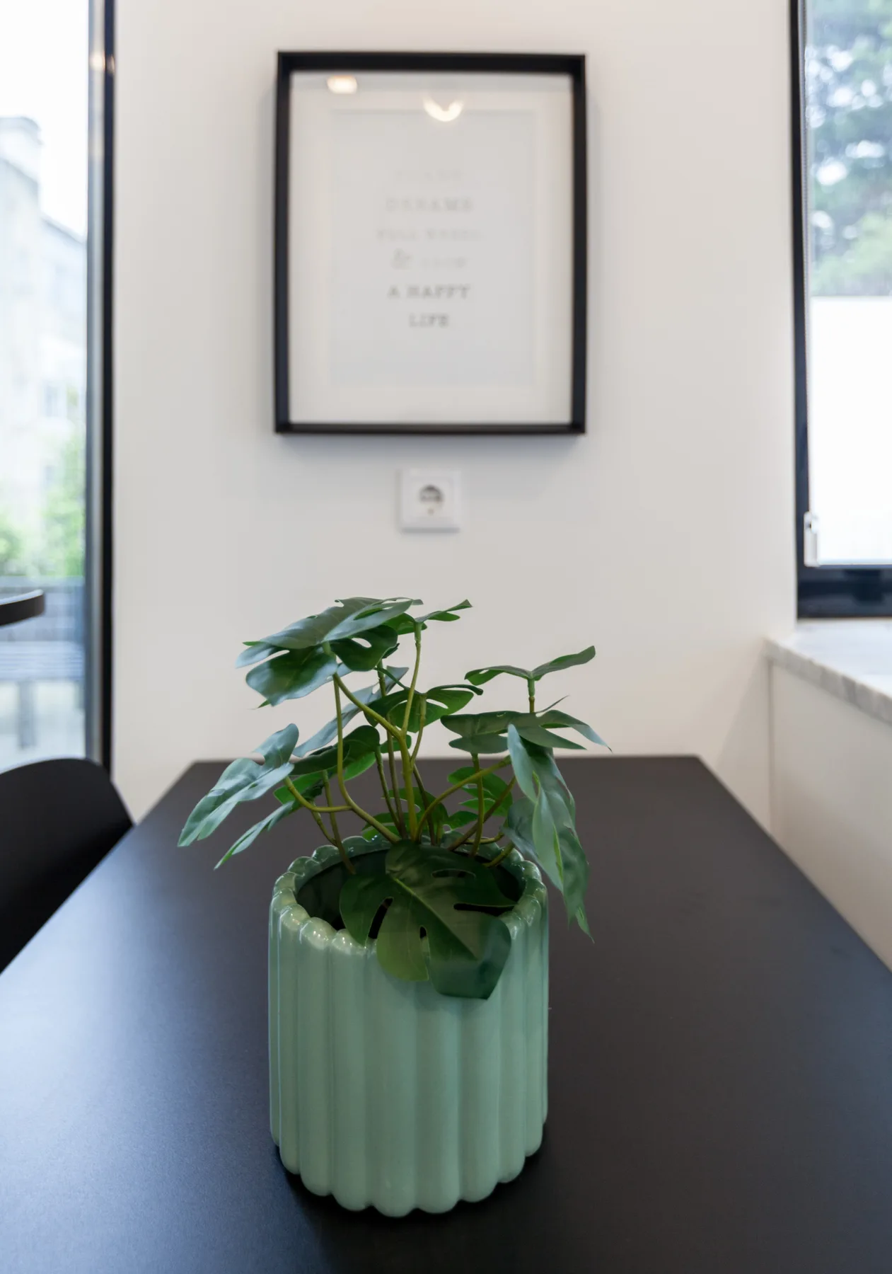A potted plant sits on a table beneath framed wall art.