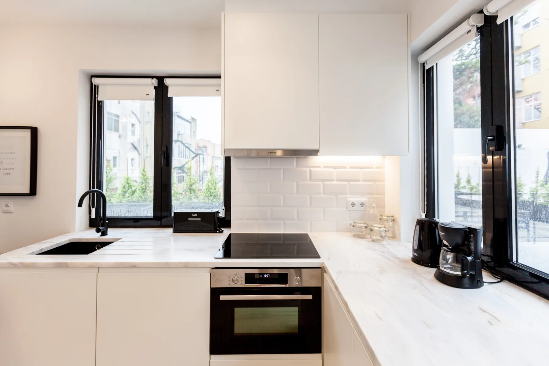 A bright kitchen with a sink, cooktop, and large windows.