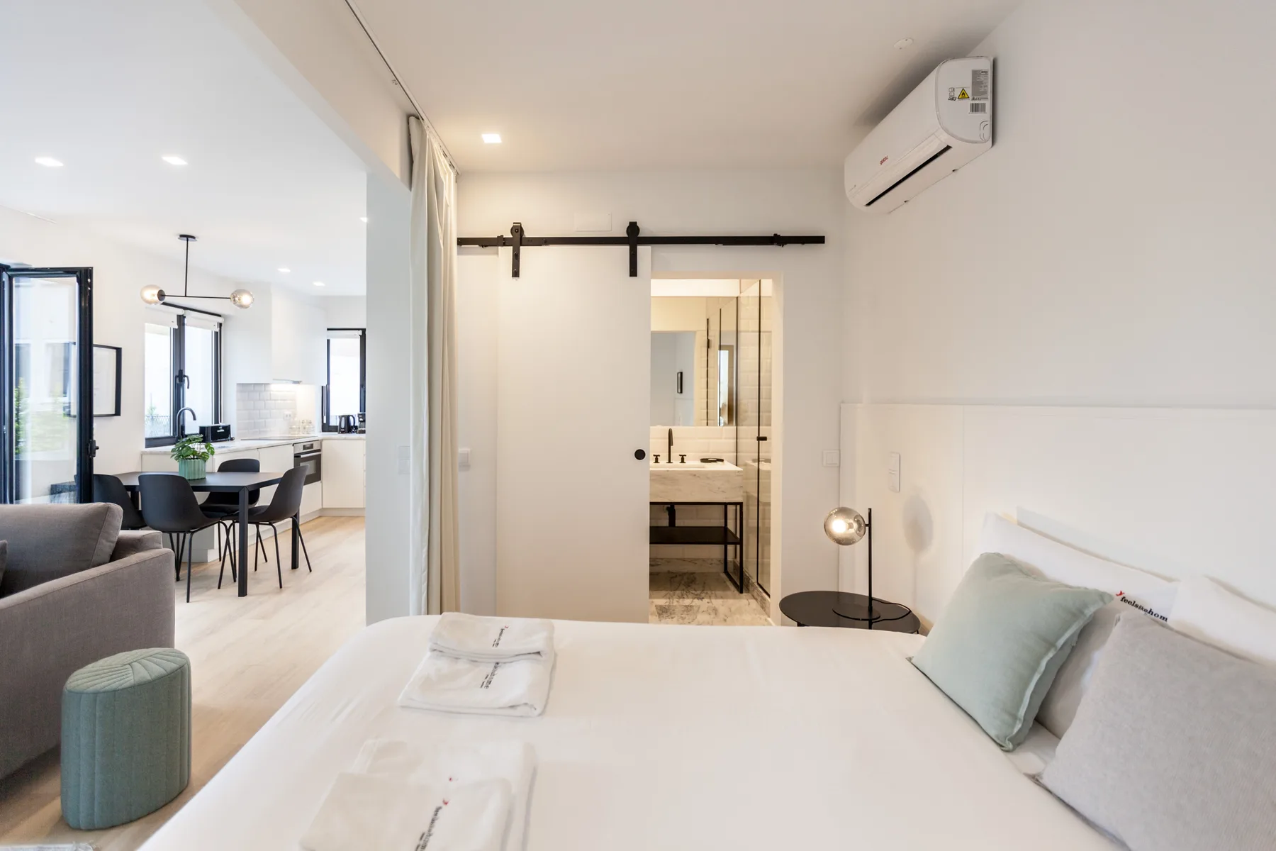 A bright bedroom opens onto a dining area and a bathroom.