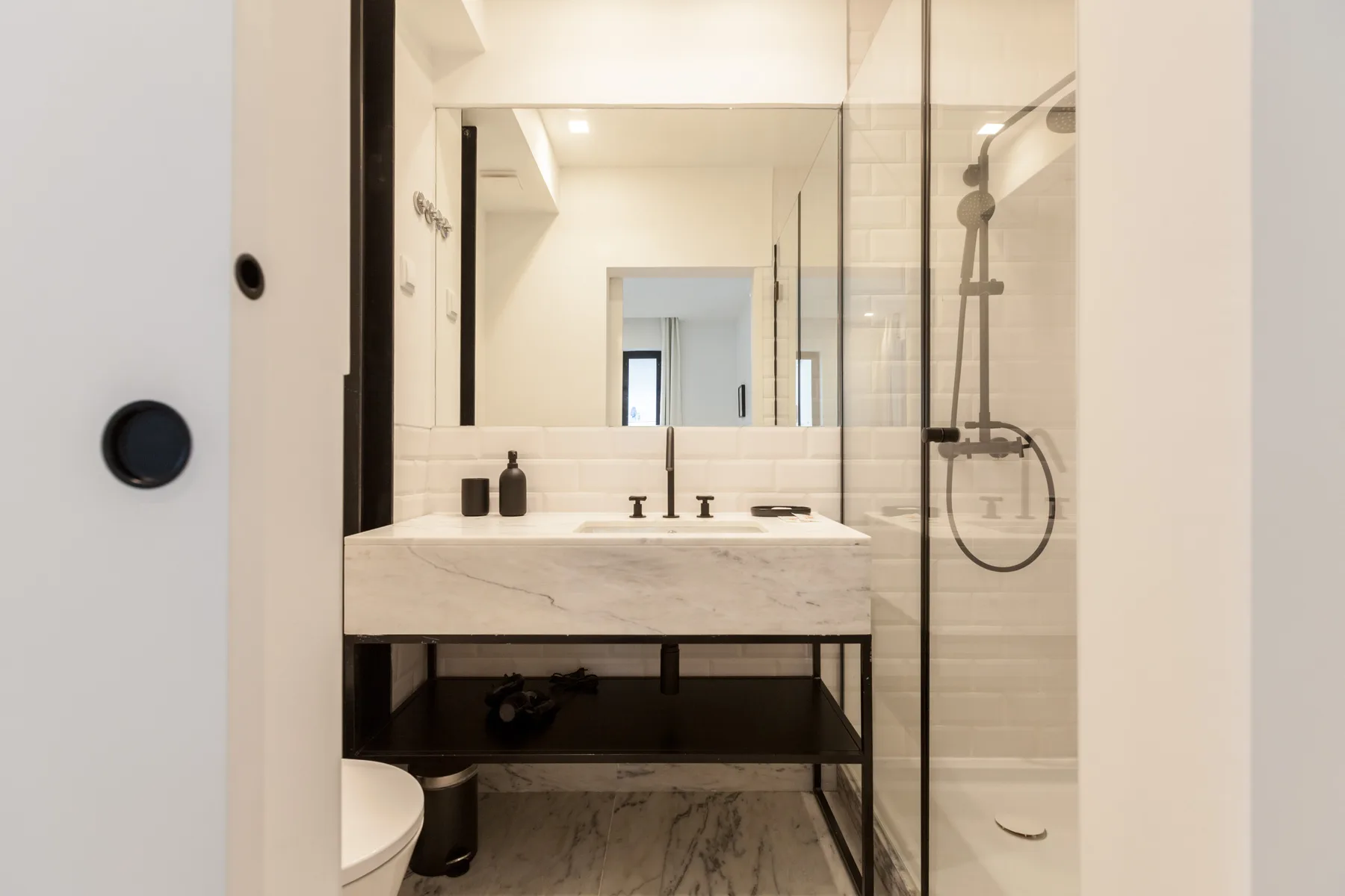 A bathroom with a sink vanity and glass-enclosed shower.