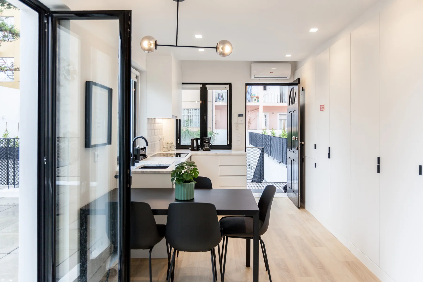 A bright studio interior with a dining table and a compact kitchen.