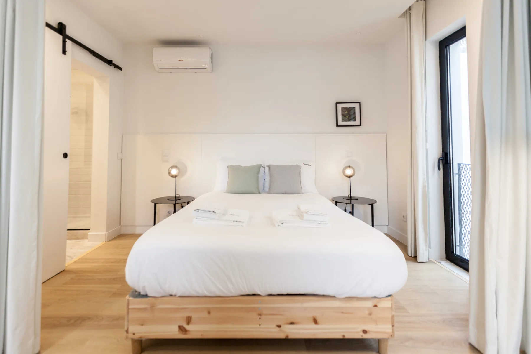 A bright bedroom with a neatly made bed and bedside tables.