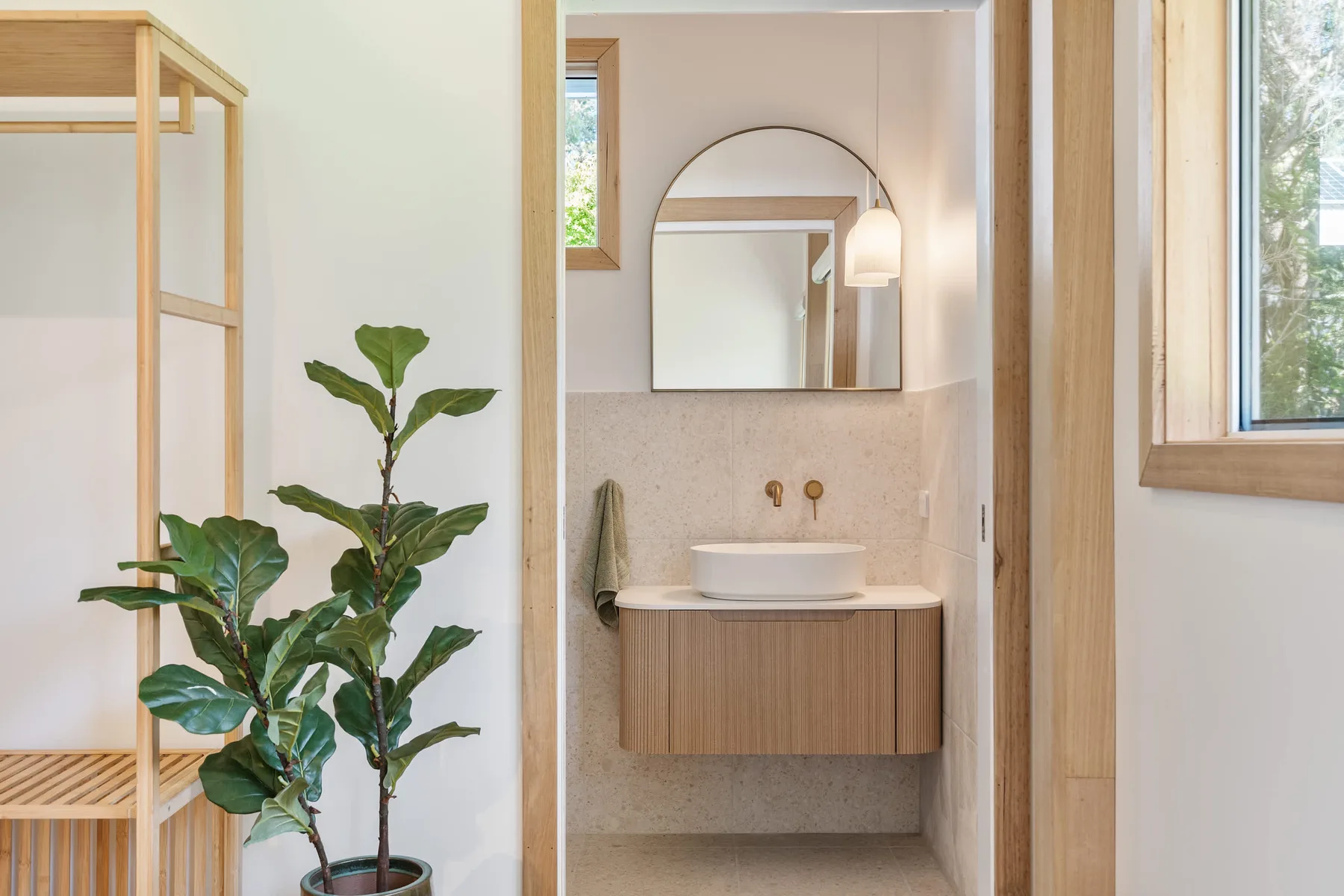 A bathroom vanity with a basin and mirror is visible beside a leafy plant.