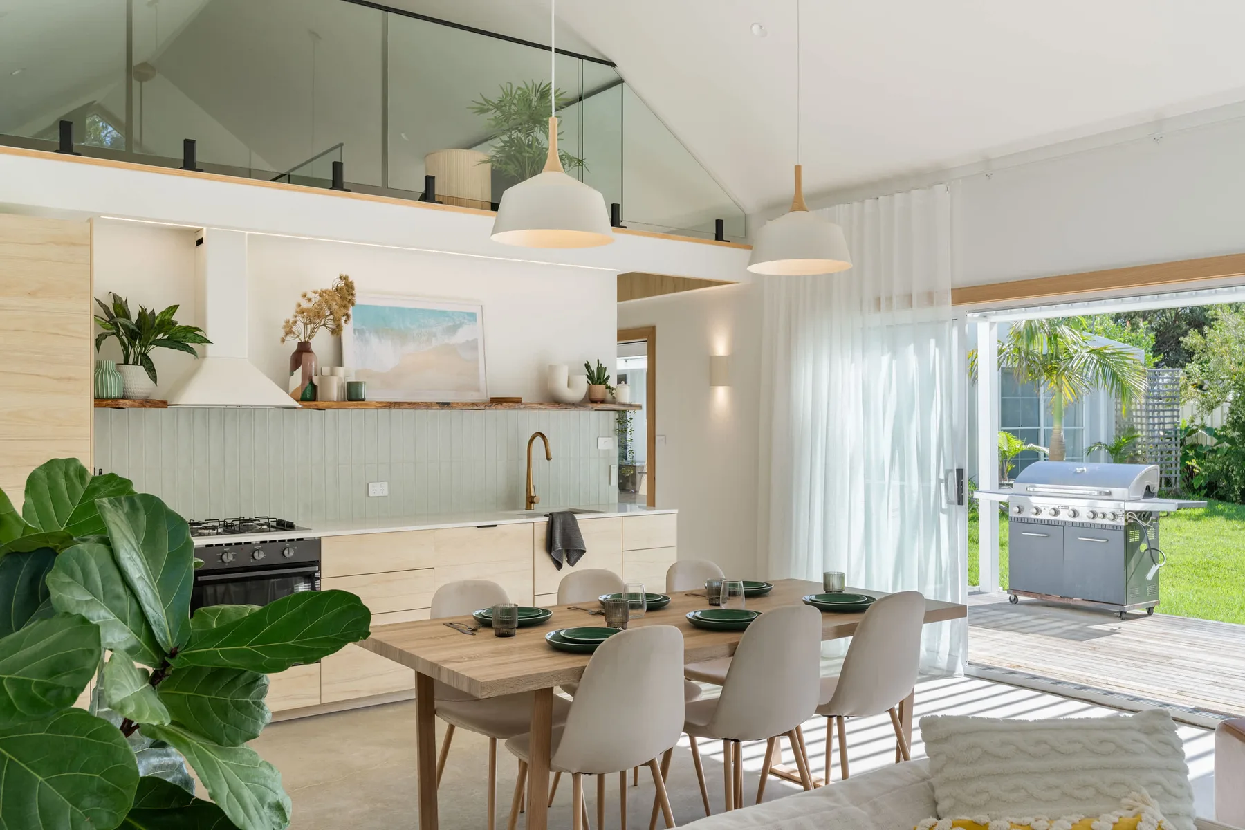 An open-plan kitchen and dining area with a table beside glass doors.