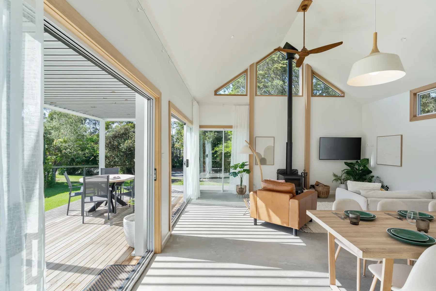 A bright living room opens onto a deck with outdoor seating.