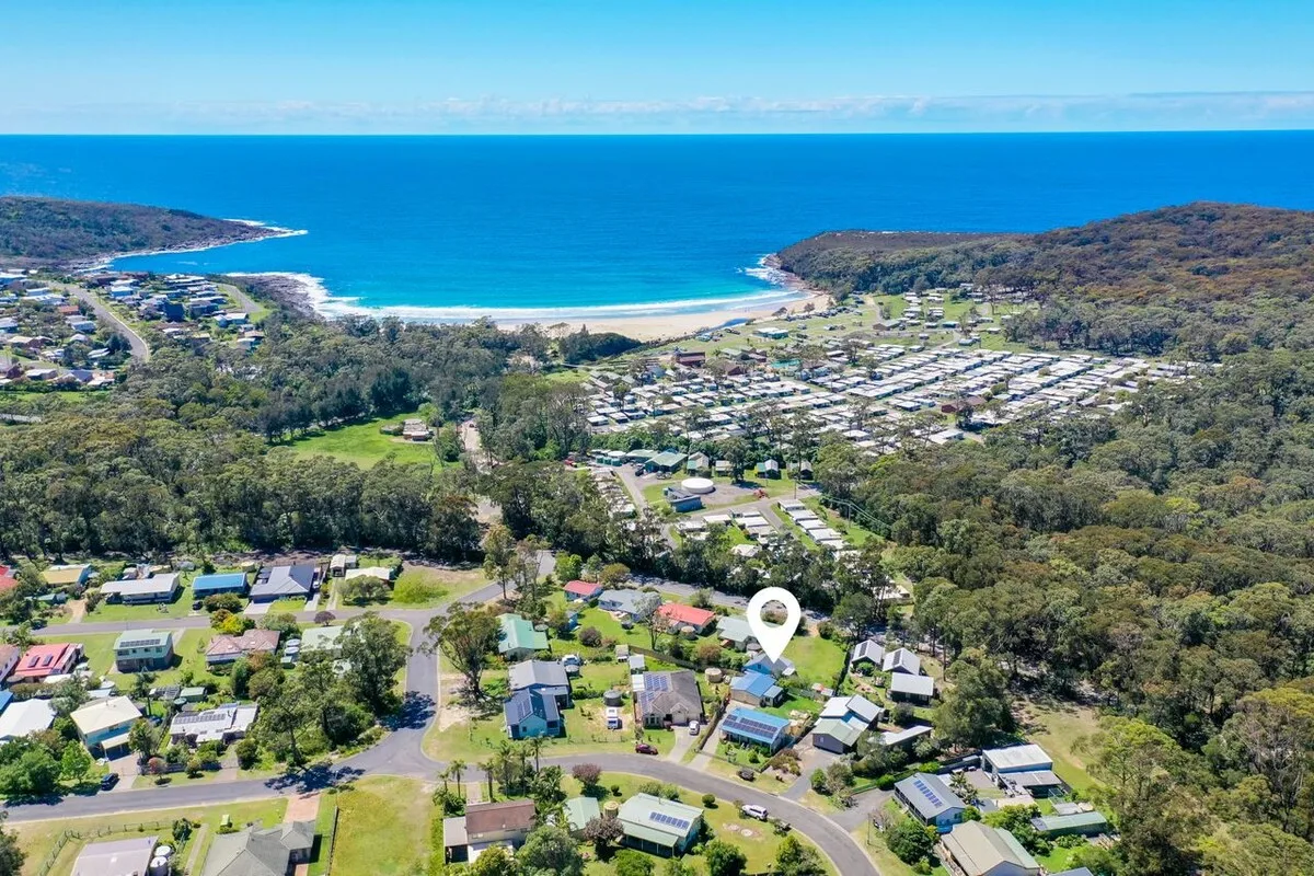 An aerial view of a coastal neighborhood with the ocean and beach beyond.