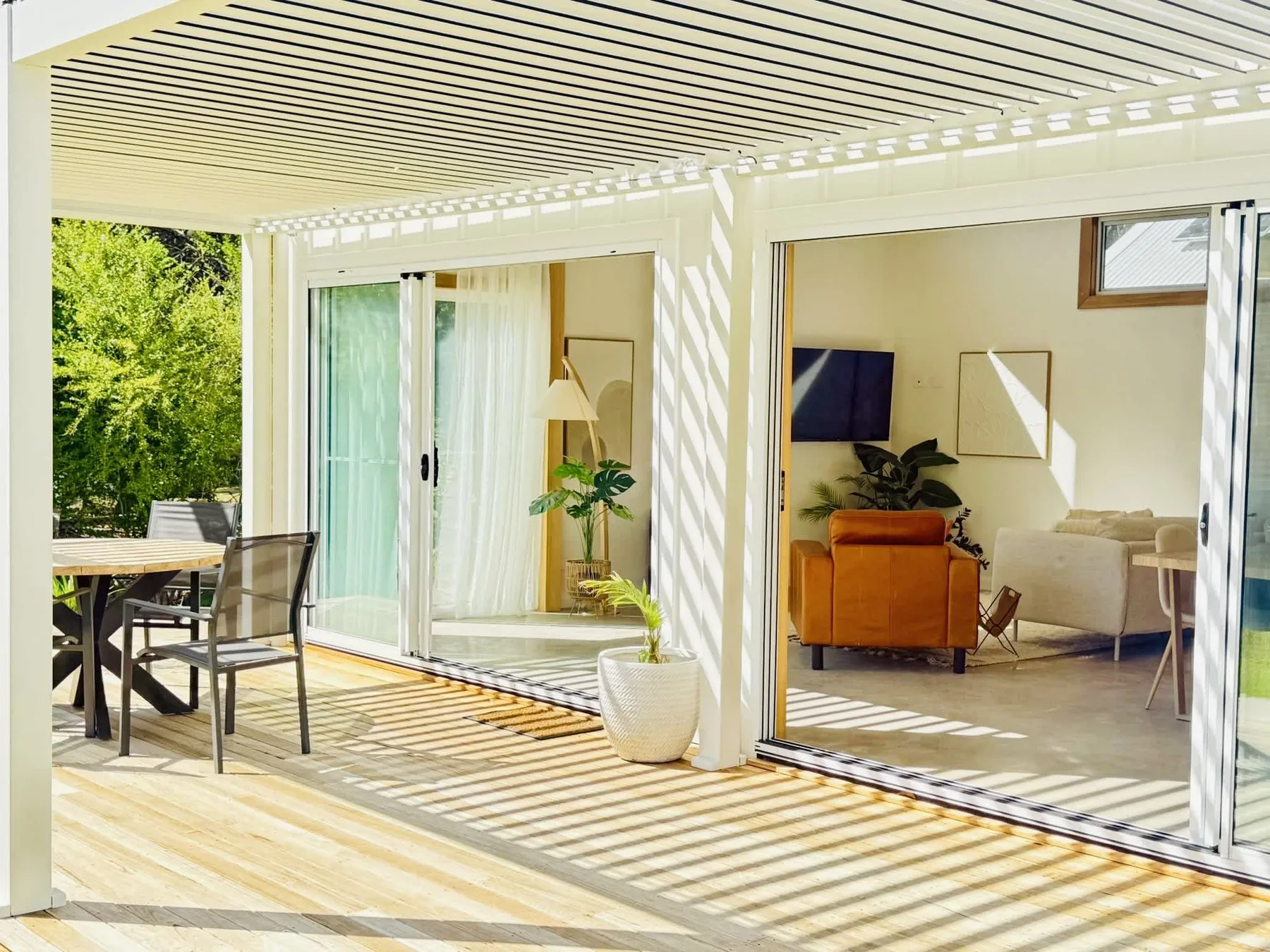 A sunny patio with outdoor seating opens onto a bright living room.