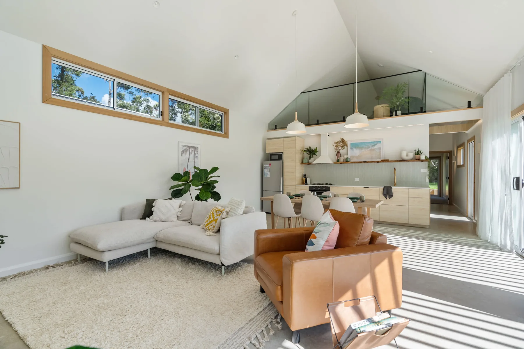 A bright open-plan living area with seating and a kitchen.