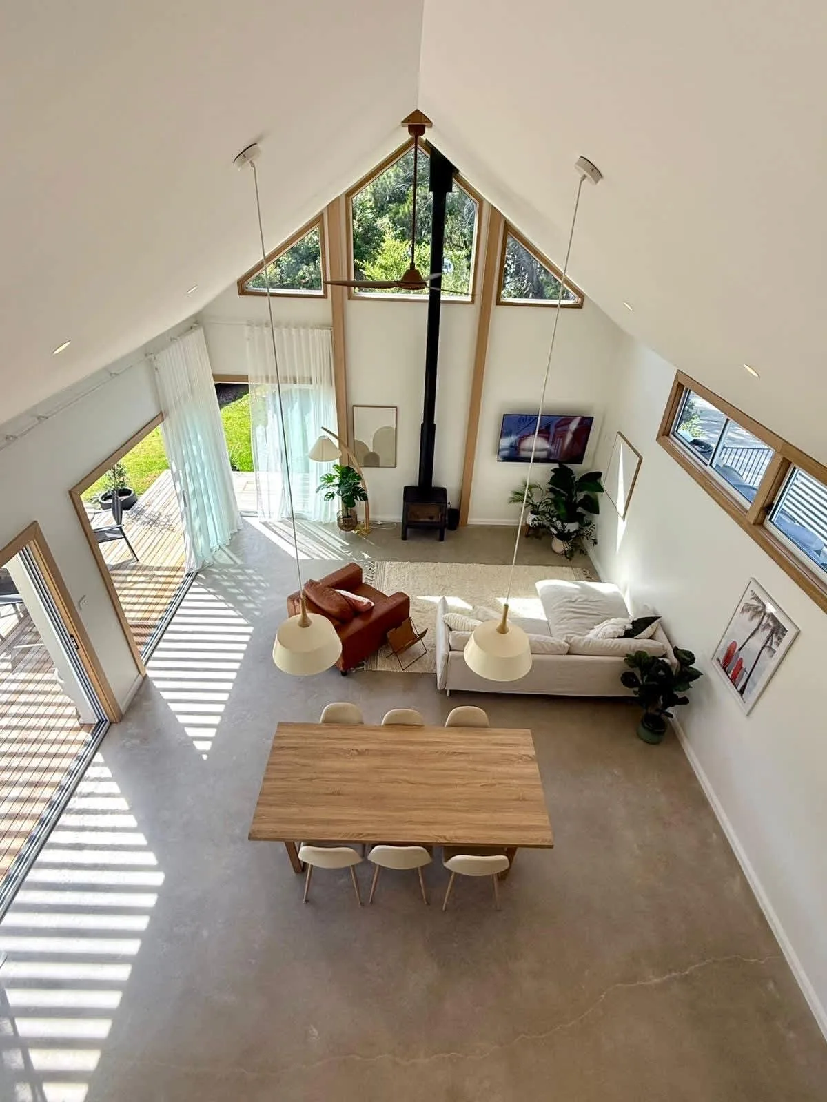 A bright open-plan living and dining area with a high pitched ceiling and large windows.