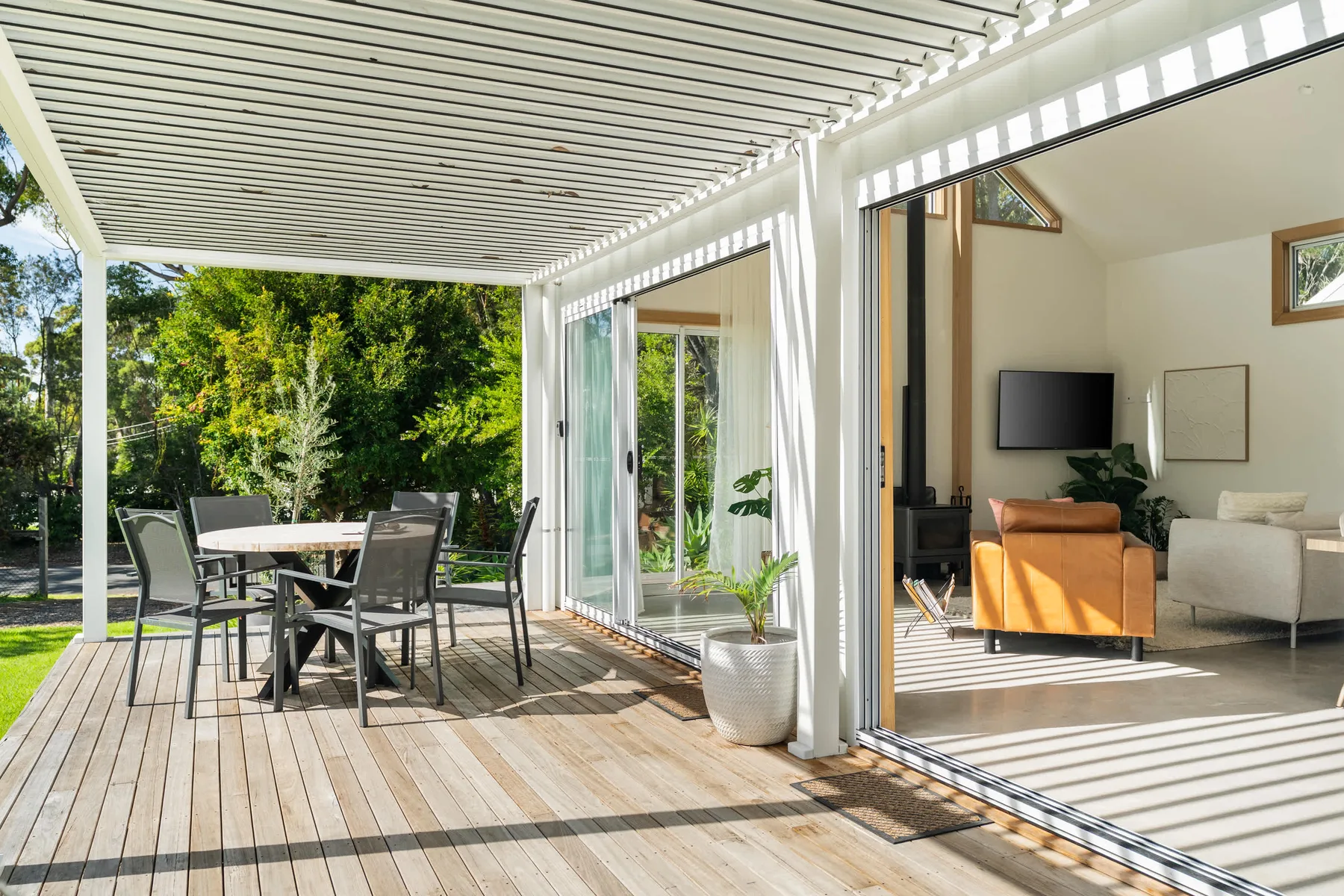A covered patio with outdoor seating opens onto a bright living area.