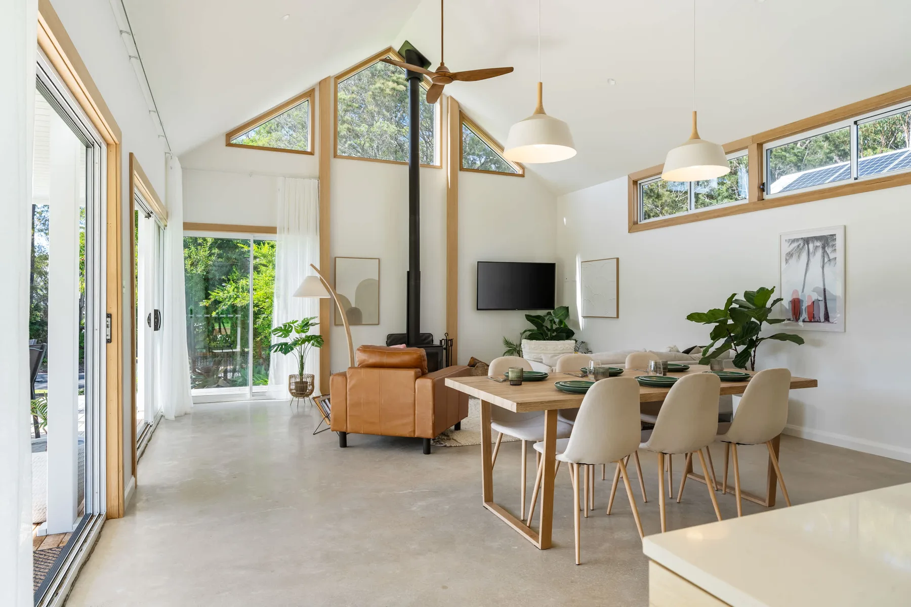 A bright open-plan living and dining room with large windows and a dining table.