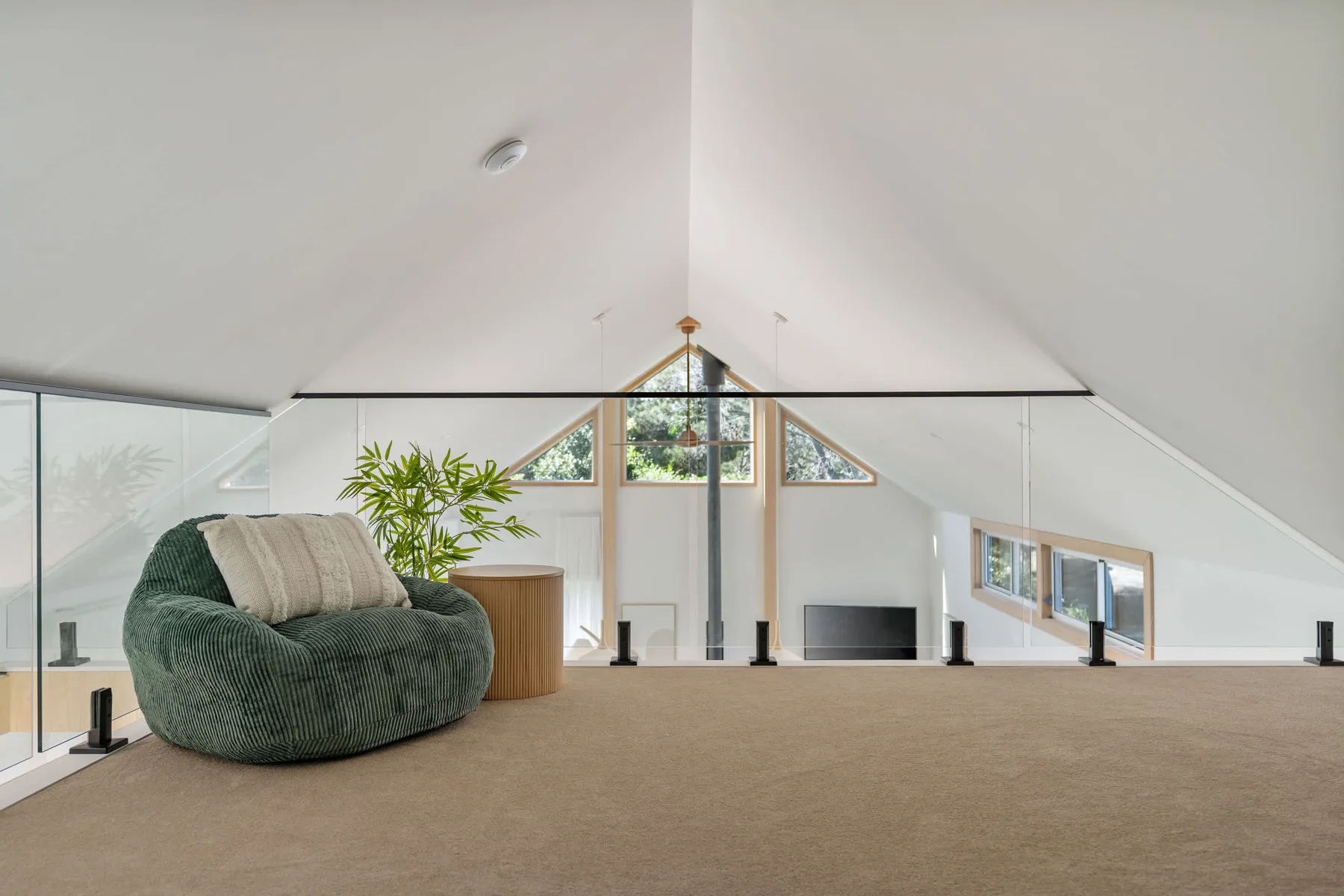 A bright loft seating area features a green chair beside large windows.