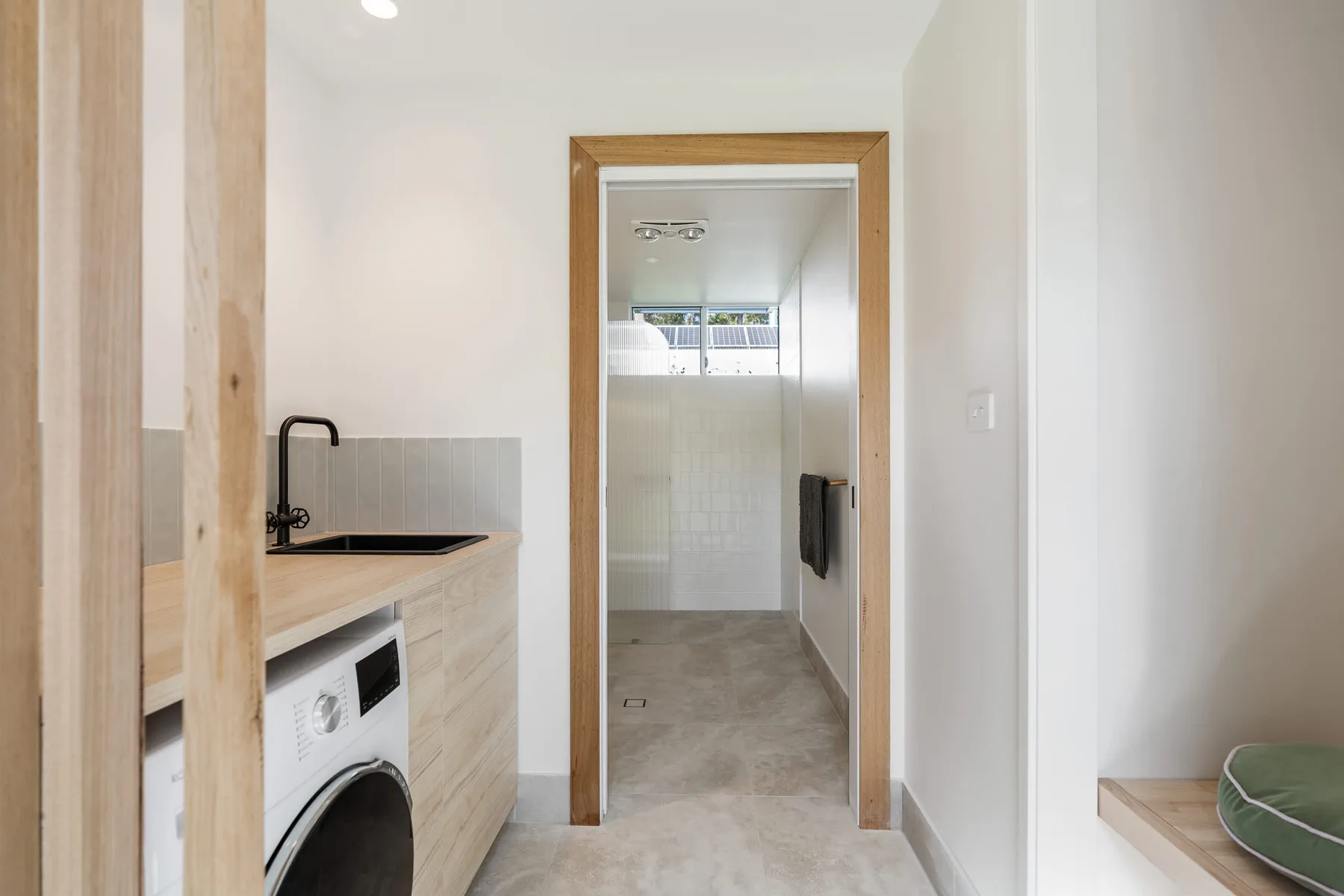 A laundry area with a washing machine and sink opens onto a tiled bathroom.