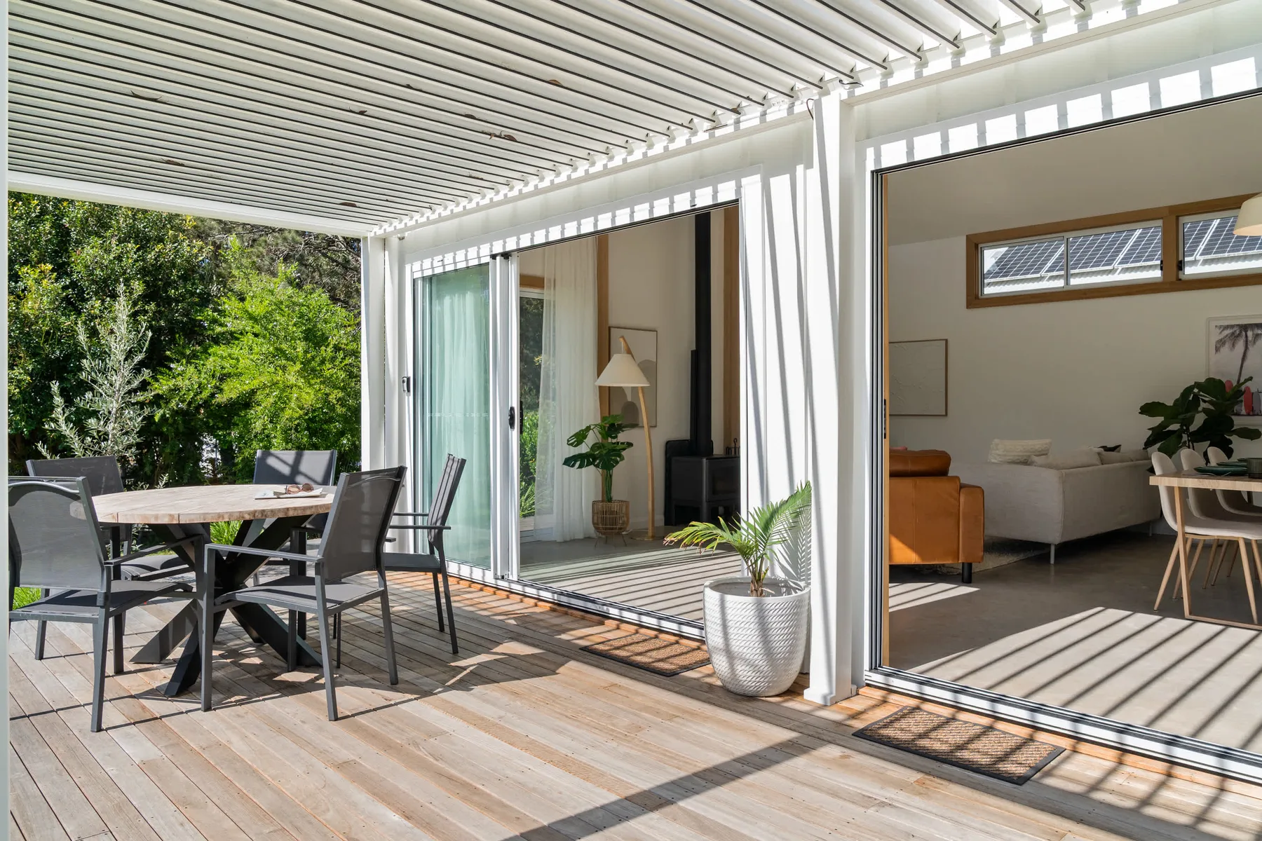 A bright patio with outdoor seating opens onto a living room through sliding glass doors.
