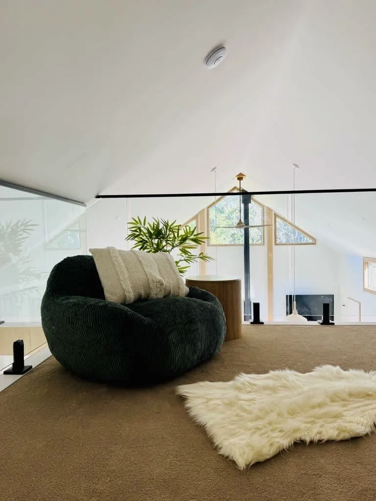 A bright loft living area with seating, a fireplace, and a light-colored rug.