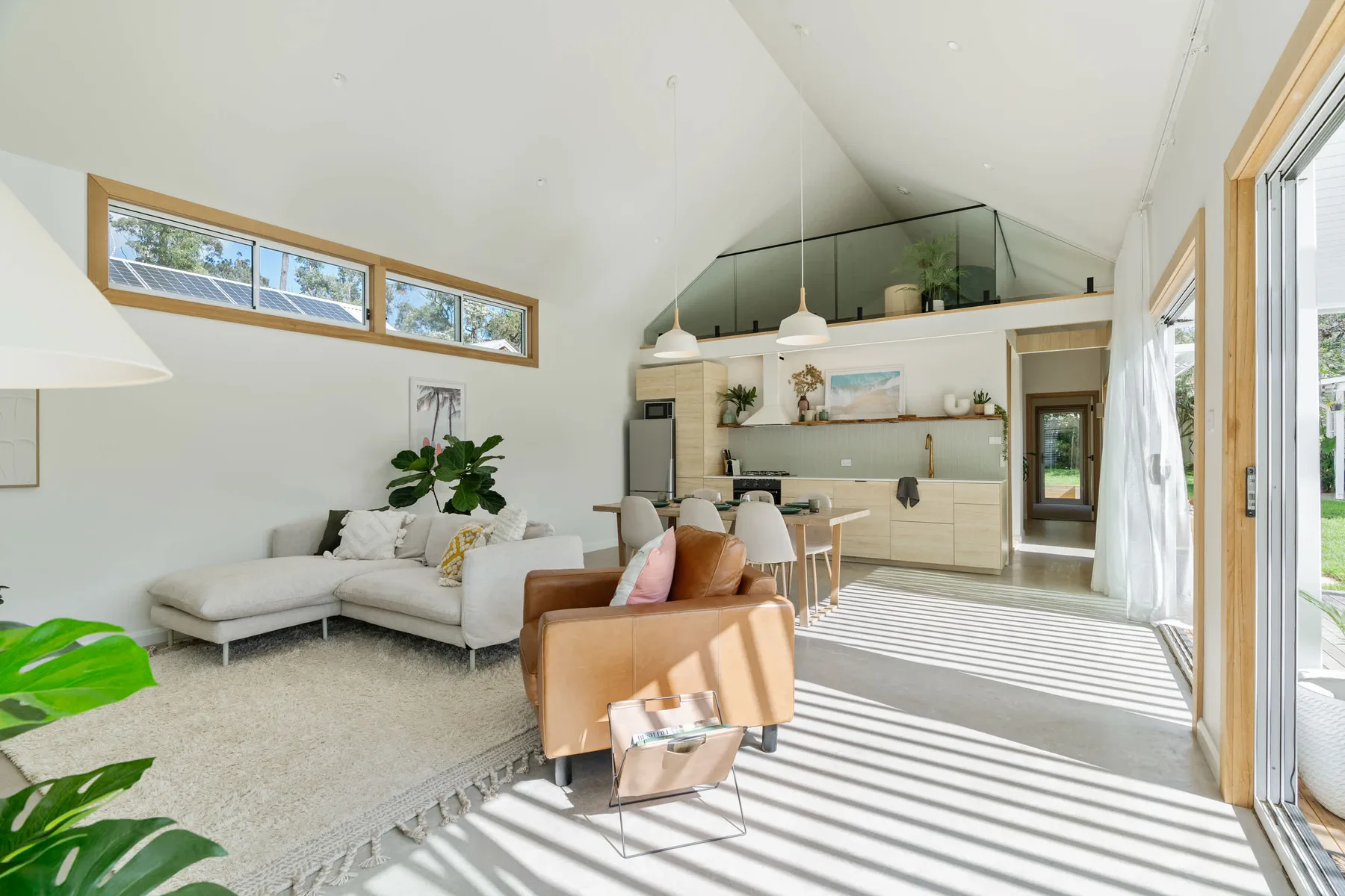 A bright open-plan living room with seating beside a kitchen and dining area.