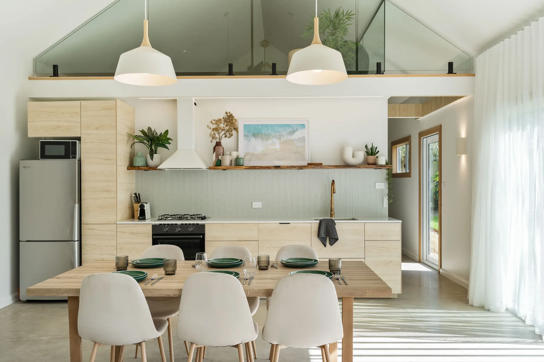 A bright open-plan kitchen and dining area with a table set beside the kitchen.