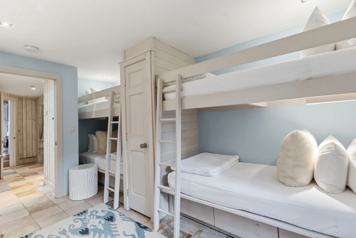Dormitorio con literas blancas y paredes azul claro.