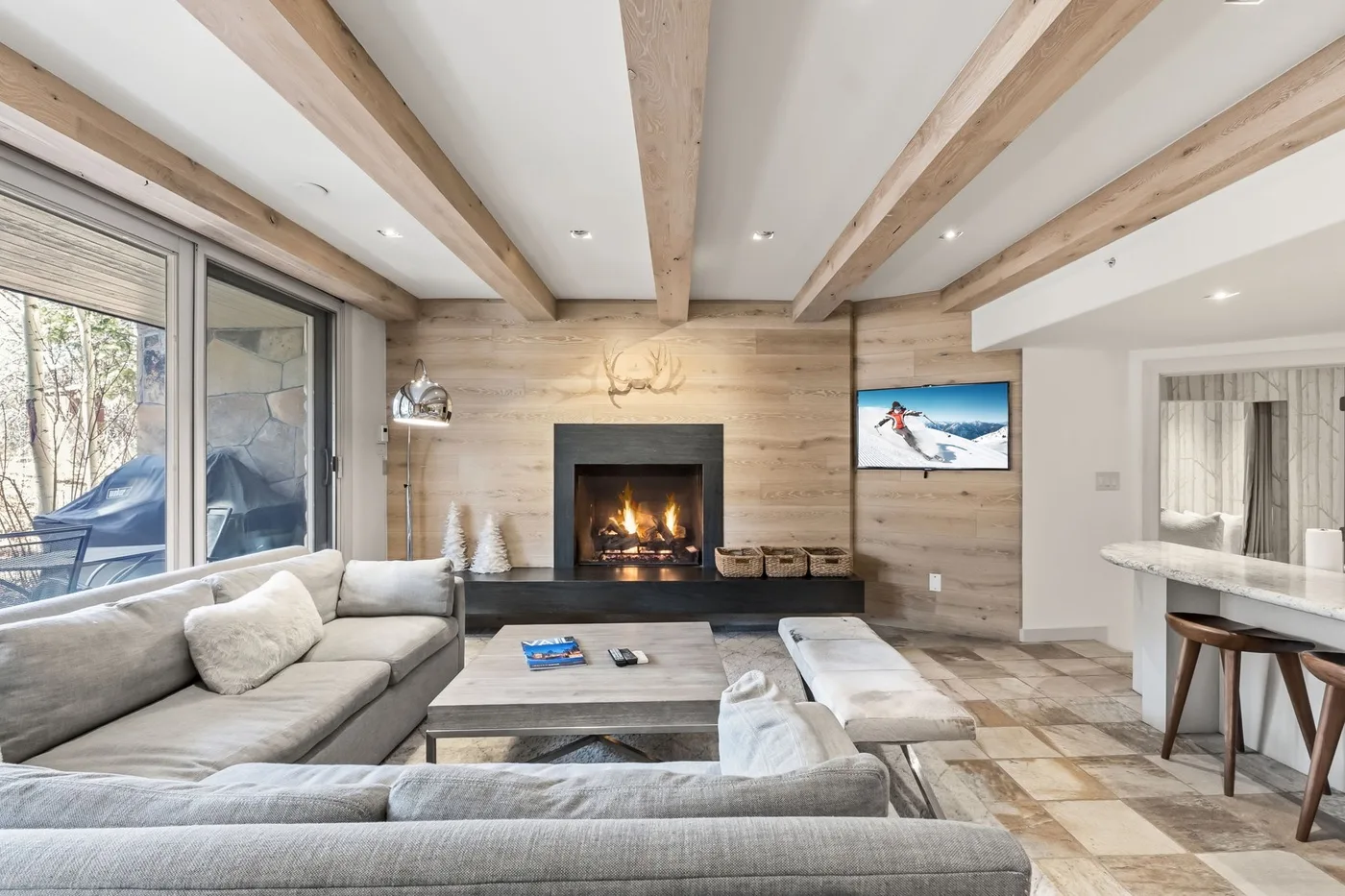 Una sala de estar con chimenea, asientos y vigas de madera expuestas en el techo.
