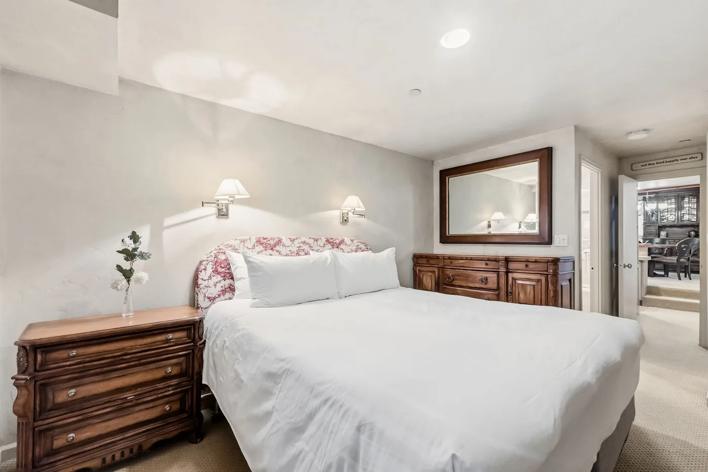 Un dormitorio con una cama grande, mesitas de noche y un cuadro sobre una cómoda.