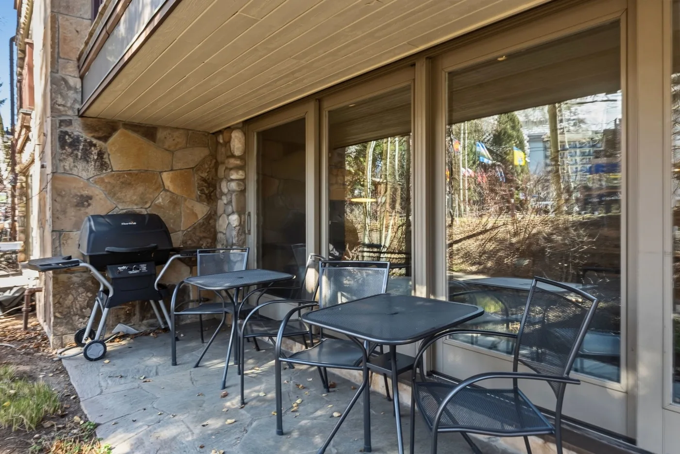 Un patio con asientos al aire libre y una parrilla junto a grandes ventanas.