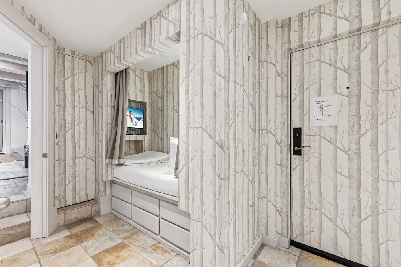 Un dormitorio con una cama en un nicho de pared y papel pintado estampado.