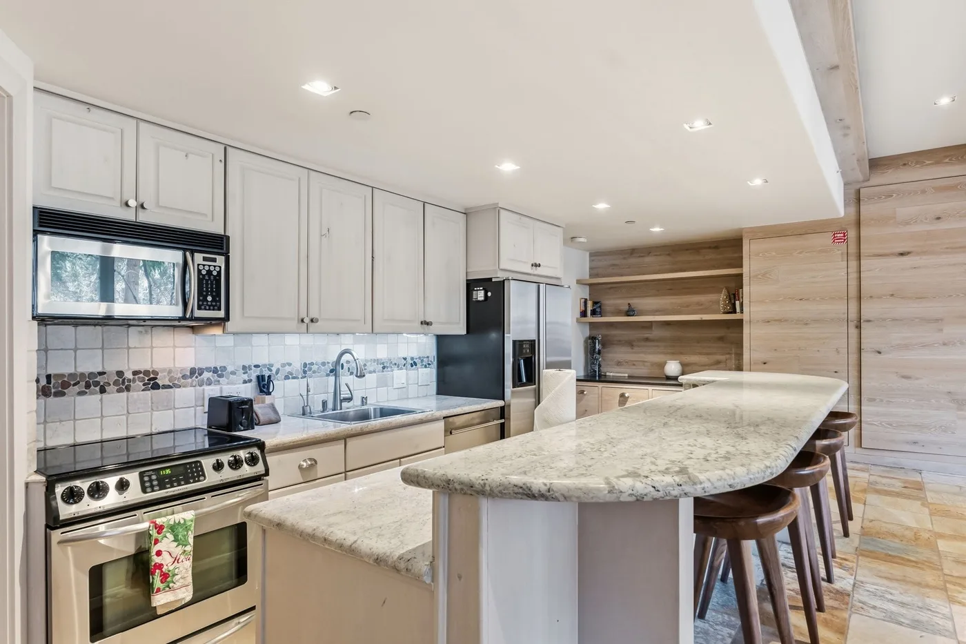 Una cocina luminosa con gabinetes claros, salpicadero de azulejos y una isla amplia.